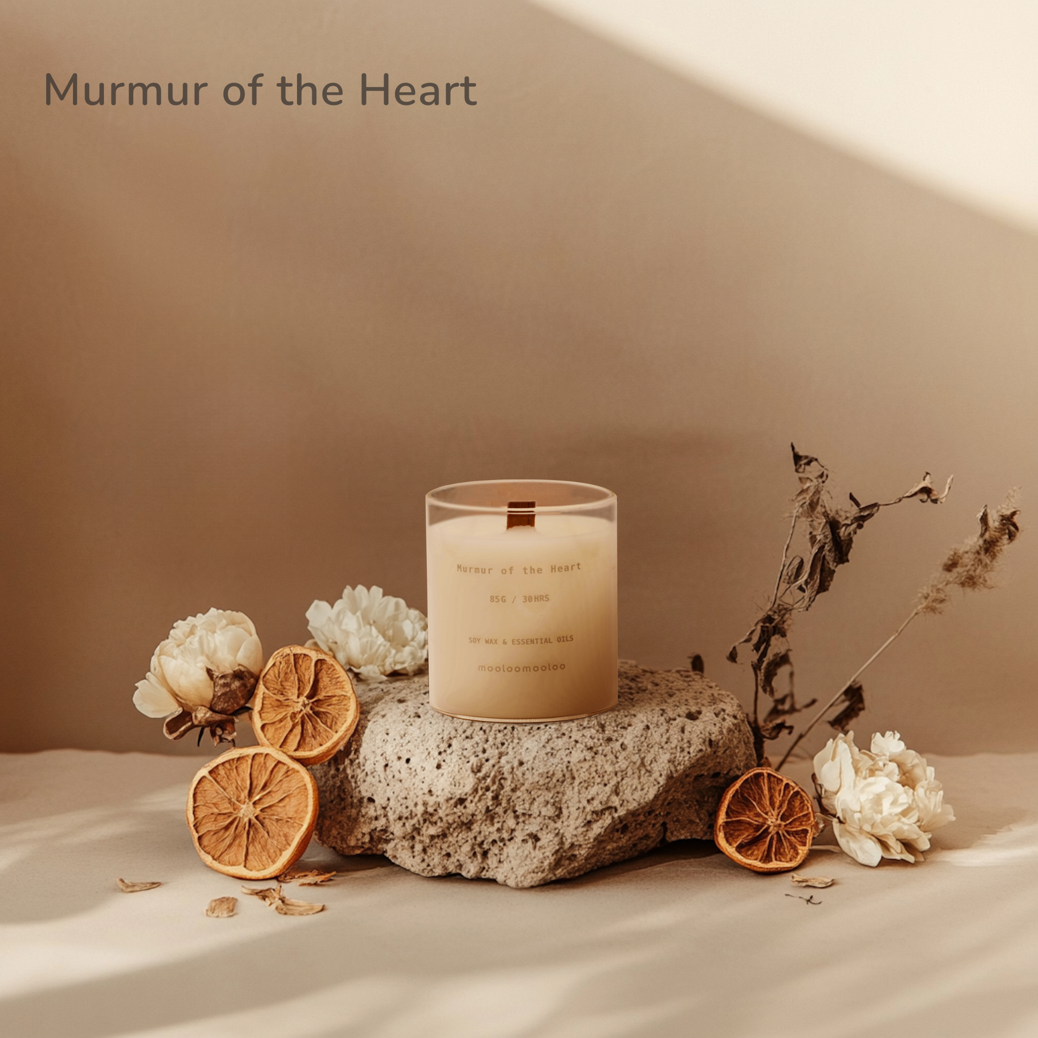 Murmur of the Heart crystal candle by Mooloomooloo placed on a natural stone with dried citrus and white flowers, softly lit in warm neutral tones.
