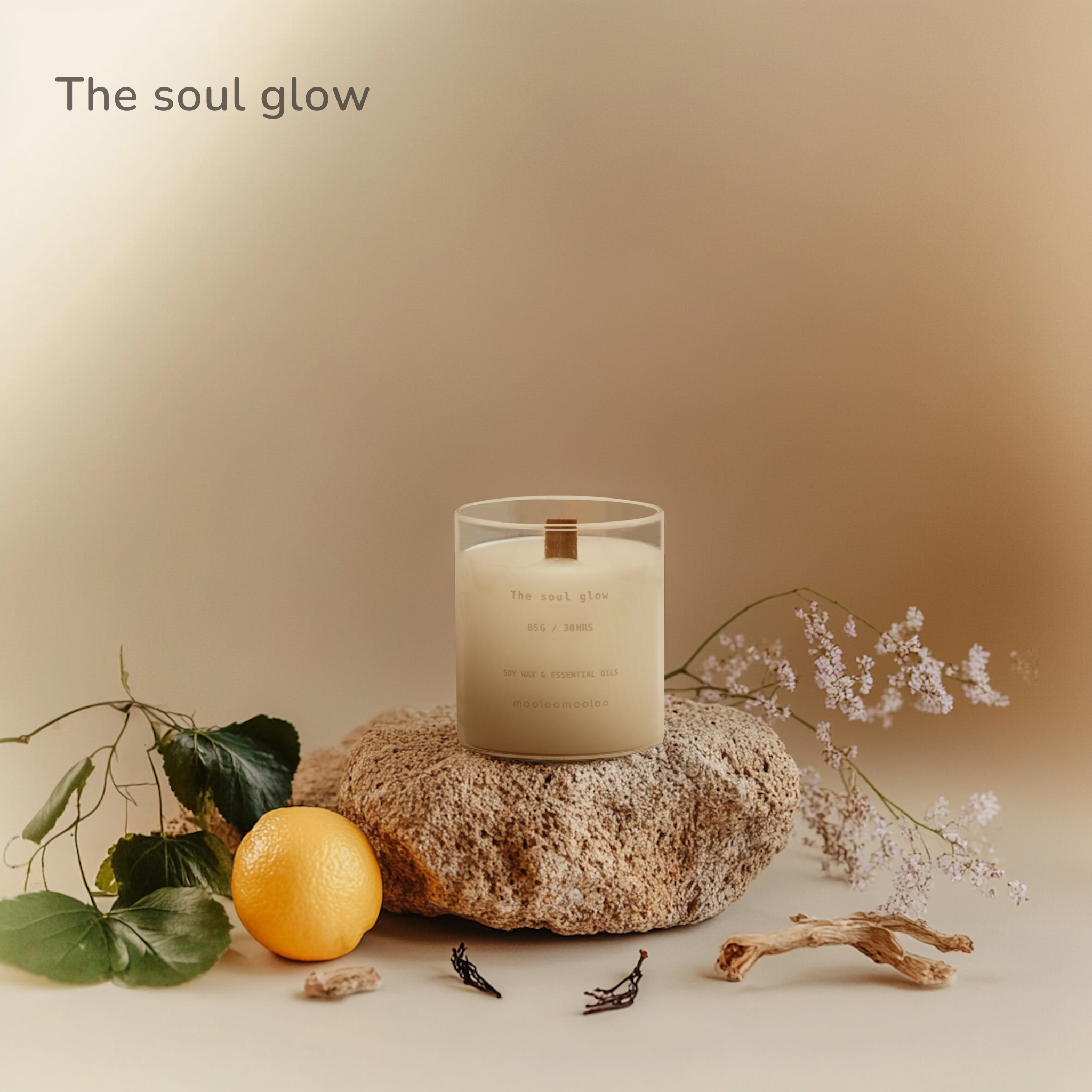 The Soul Glow scented candle by Mooloomooloo placed on a textured stone, surrounded by lemon, botanical leaves, dried wood, and soft lilac blooms in warm natural light.