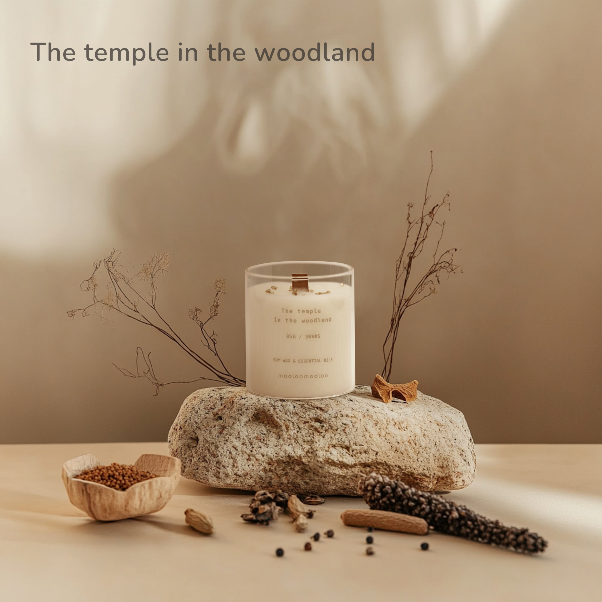 The Temple in the Woodland scented candle by Mooloomooloo placed on a textured stone, surrounded by dried herbs, peppercorns, cardamom, and natural twigs in a warm, earthy setting.